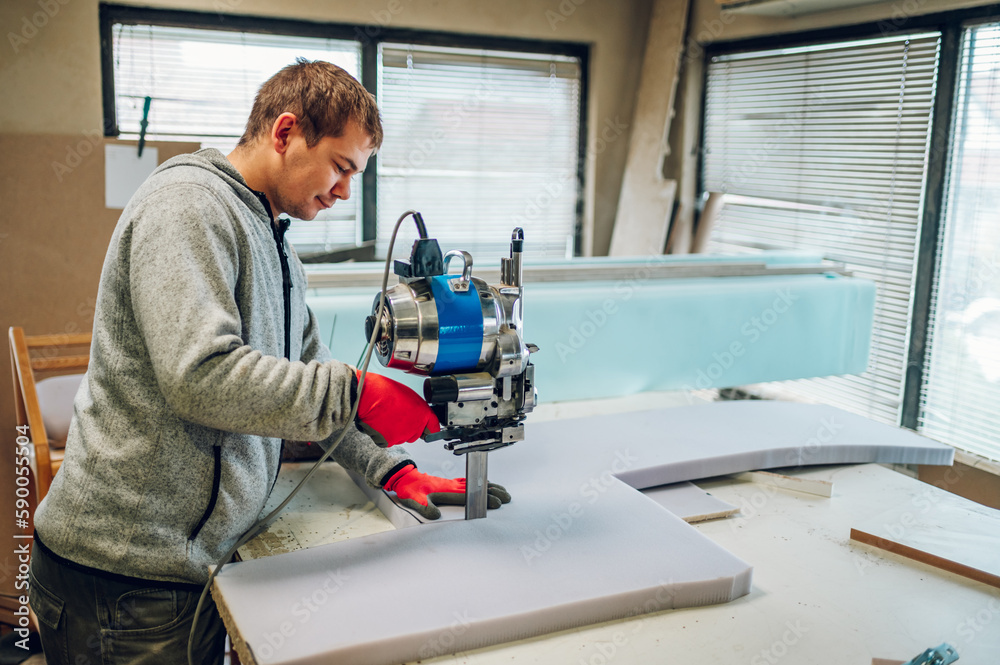 An artisan is making furniture parts by using a foam cutter at his workshop. An artisan is making furniture parts by using a foam cutter at his workshop.