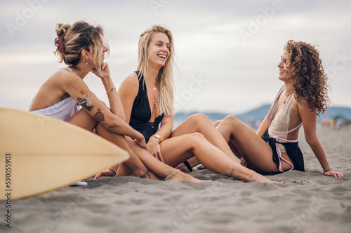 Portrait of a three attractive woman friends sitting on a sandy beach