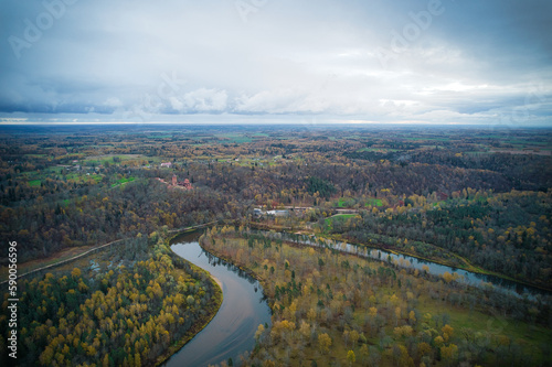 Above aerial shot of green pine forests and yellow foliage groves with beautiful texture of golden treetops. Beautiful fall season scenery in evening. Mountains in autumn colors in golden time