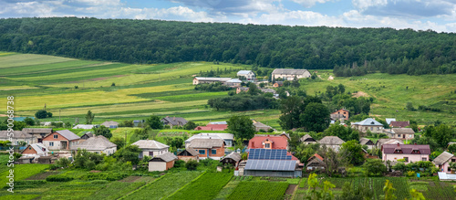 Top view of solar panels in yard, houses, gardens and estates and nature landscape on horizon