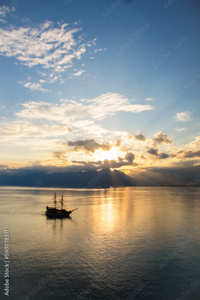 Fototapeta premium Landscape of boat - yacht in the Mediterranean sea with mountains in the distance during the sunset, Antalya, Turkey