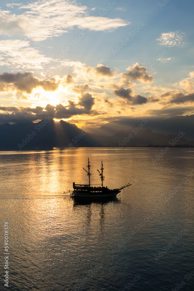 Landscape of boat - yacht in the Mediterranean sea with mountains in the distance during the sunset, Antalya, Turkey