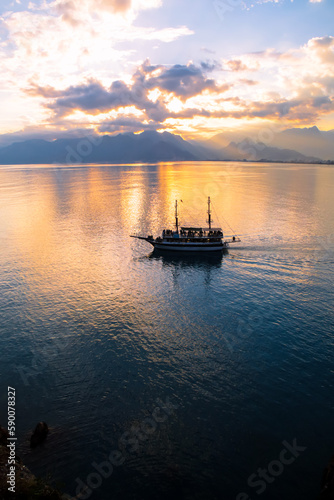 Landscape of boat - yacht in the Mediterranean sea with mountains in the distance during the sunset, Antalya, Turkey