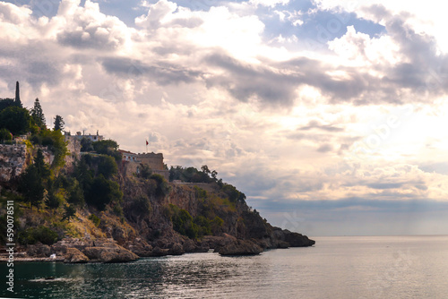 Coast of Antalya harbour with cliff and stones in the sea during a cloudy day