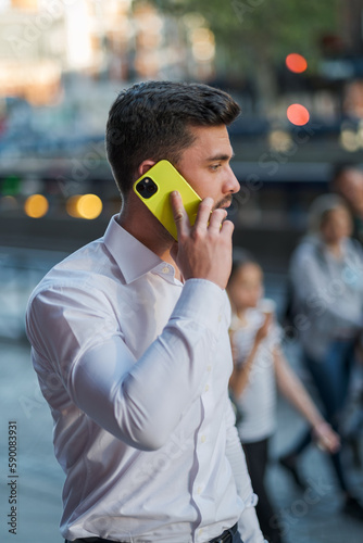 A boy in a white shirt talking on the phone with an out-of-focus background.