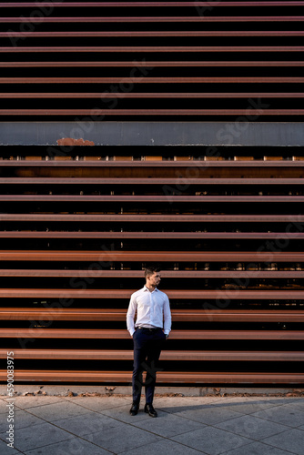 Boy dressed in a white shirt waiting in the background of a red building