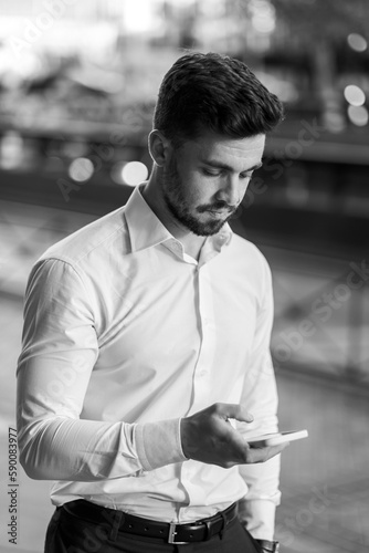 A boy in a white shirt, looking at the phone with an out-of-focus background.
