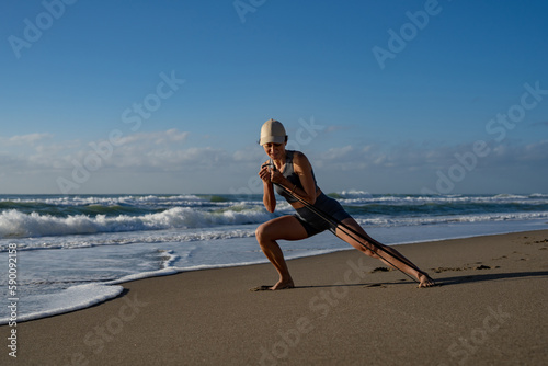 beautiful young girl goes in for sports on the seashore doing lunges