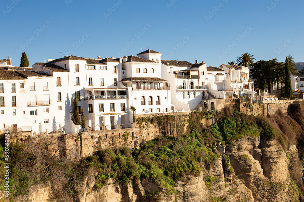Landscape of old white buildings on the rocks of the gorge on a sunny day. Landmark of the city of Ronda, Malaga, Andalusia, Spain. Landscape of old white buildings on the rocks of the gorge on a sunny day. Landmark of the city of Ronda, Malaga, Andalusia, Spain.
