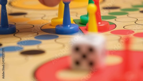 People play Ludo or Pachisi board game on beautiful wooden play board. Ludo is a strategy board game for two to four players. 4K resolution family board game video. photo