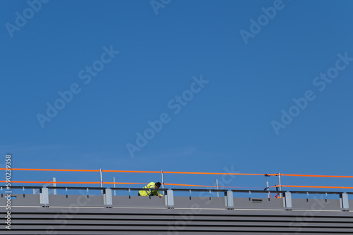 Worker on flat roof with orange temporary railing