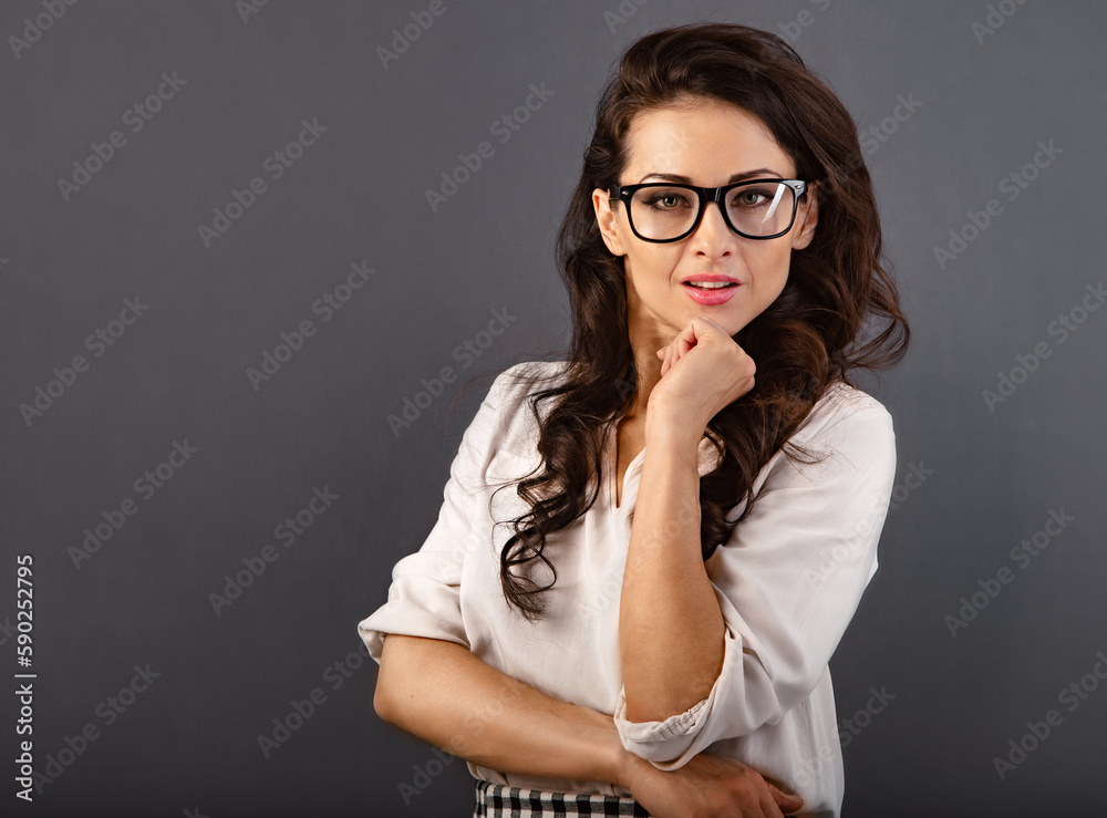 Beautiful thinking make-up happy brunette business woman looking happy in eyeglasses in white silk blouse and curly hair style on grey background with empty copy space. Closeup