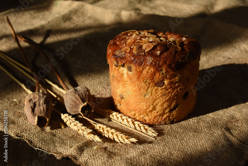 Easter cake decorated with almond is on a sacking tablecloth. Wheat spikes and poppy heads are near.Sunlight and shadows