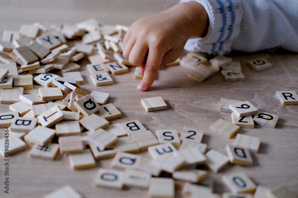 hands close-up, small child 3 years old plays wooden alphabet blocks, makes up words from letters, dyslexia awareness, learning difficulties, human brain development, happy childhood, selective focus - obrazy, fototapety, plakaty 