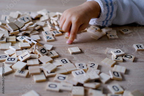 hands close-up, small child 3 years old plays wooden alphabet blocks, makes up words from letters, dyslexia awareness, learning difficulties, human brain development, happy childhood, selective focus photo