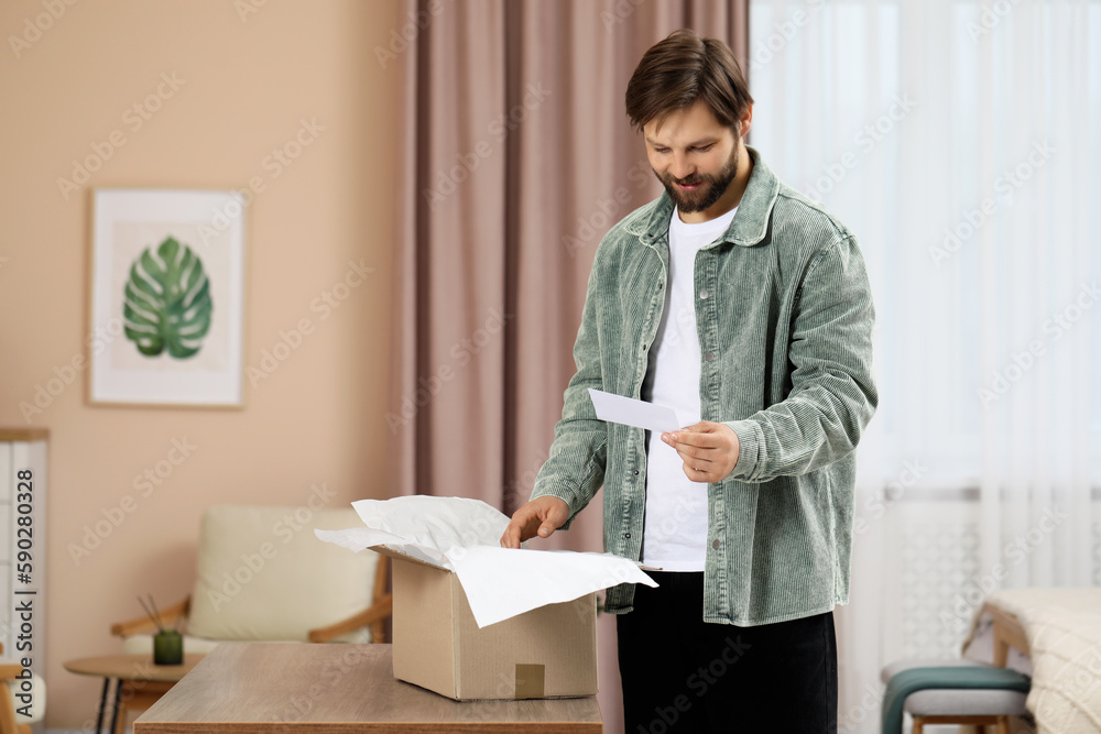 Happy man with greeting card near parcel at home. Internet shopping Happy man with greeting card near parcel at home. Internet shopping