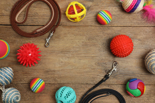 Flat lay composition with dog leashes and toys on wooden background, space for text