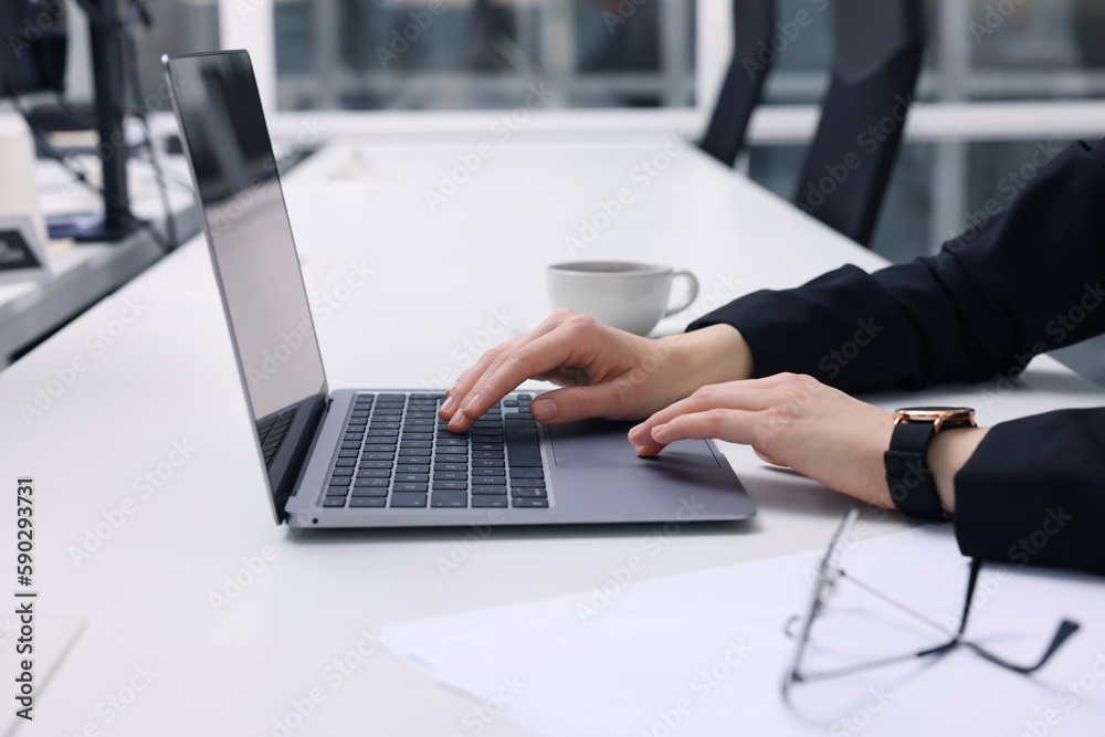 Woman working with laptop at white desk in office, closeup Woman working with laptop at white desk in office, closeup