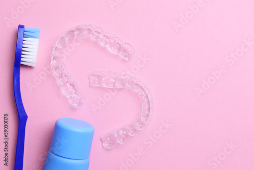 Transparent plastic dental aligners and care products on a colored background