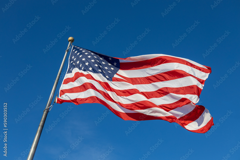 Close up view of an American flag waving on a flagpole, with blue sky background and copy space
Close up view of an American flag waving on a flagpole, with blue sky background and copy space