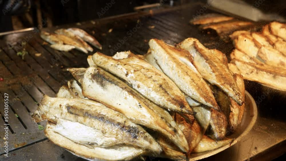 Closeup of dish full of roasted grilled fish. Cooking famous Turkish dish Balik Ekmek on street Closeup of dish full of roasted grilled fish. Cooking famous Turkish dish Balik Ekmek on street