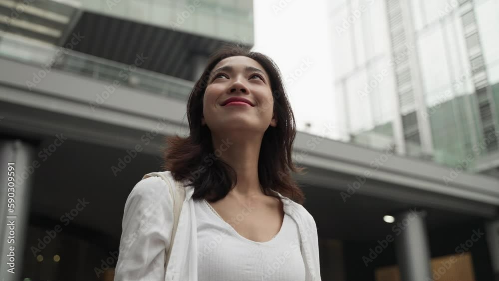 Close up of woman in white looking up sky in street surrounded by building in morning . Chinese female look up sky in city symbols the positive life attitude to life and work. Close up of woman in white looking up sky in street surrounded by building in morning . Chinese female look up sky in city symbols the positive life attitude to life and work.