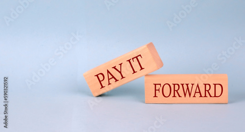 PAY IT FORWARD text on the wooden block, blue background