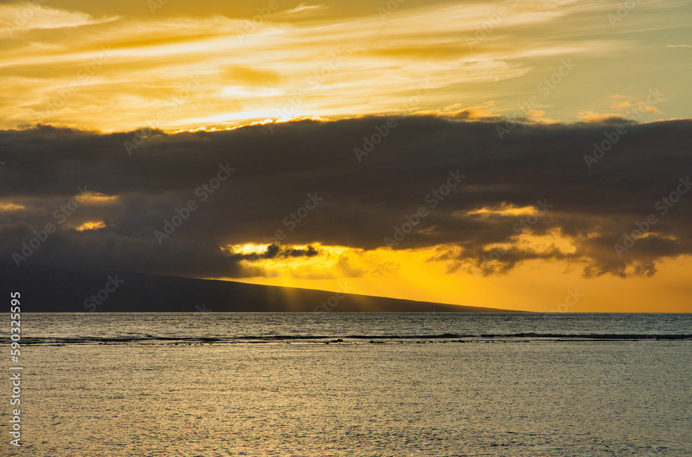 Ominous black cloud hovering over dramatic orange sunset.