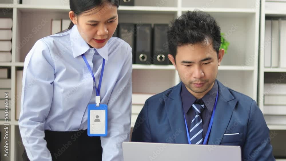 Colleagues working together in the office. The manager is teaching a new employee or intern.