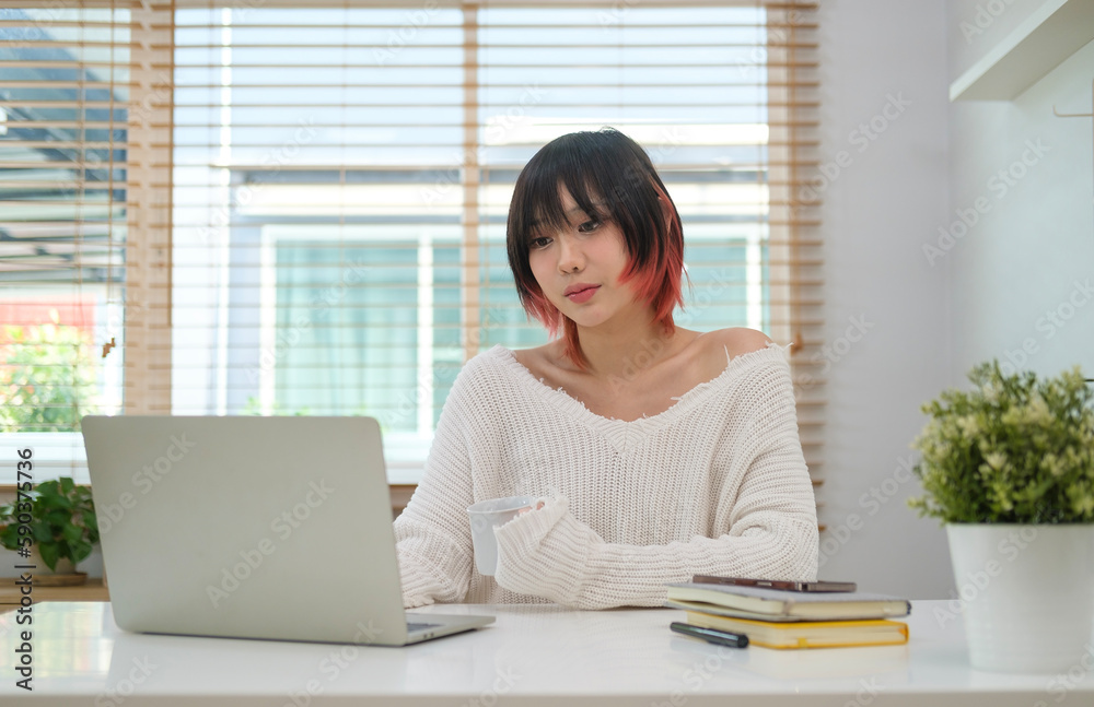 Happy young adult woman sitting in cozy living room on couch holding using laptop. Smiling casual lady chatting with friends, working or studying from home online on computer tech relaxing on sofa.. Happy young adult woman sitting in cozy living room on couch holding using laptop. Smiling casual lady chatting with friends, working or studying from home online on computer tech relaxing on sofa..