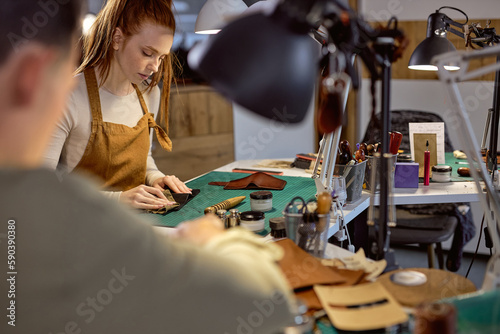 serious woman restoring old leather wallet workplace. close up photo blurred foreground
