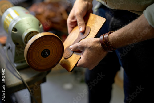 young man working on Electric Leather Burnisher Machine, close up side view cropped shot