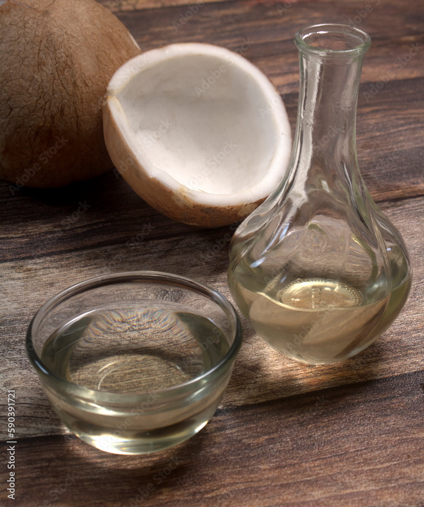 A bottle and a glass bowl of coconut oil, in wooden table A bottle and a glass bowl of coconut oil, in wooden table
