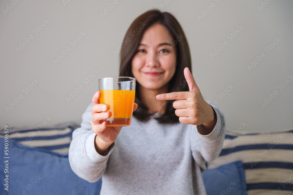 Portrait image of a woman holding and pointing finger at a glass of fresh orange juice Portrait image of a woman holding and pointing finger at a glass of fresh orange juice