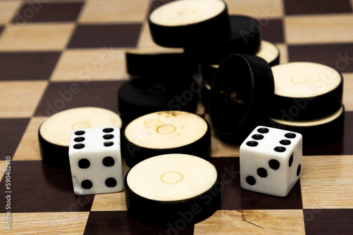 Checkers and dice on a board background . Board games. Copy space.