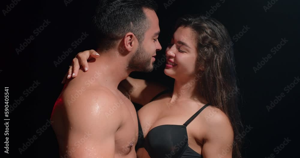 Sexy happy smiling couple is wet in the studio, slow motion, brunette girl is hugging her guy, gets pleasure from embracing in black background slow motion Sexy happy smiling couple is wet in the studio, slow motion, brunette girl is hugging her guy, gets pleasure from embracing in black background slow motion