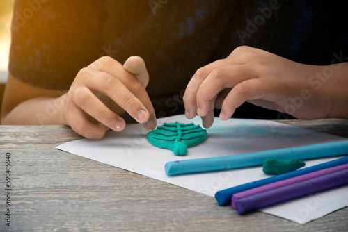 An autistic boy molding different shapes of colored plasticine prepared by parents at home in order to develop various aspects in their son which has slower brain development than normal children.