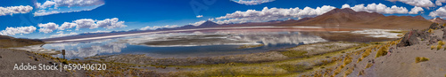 Scene of salt lagoon reflecting mountains and clouds as if in a mirror.