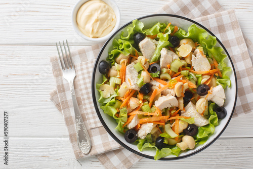Italian salad with chicken, mushrooms and fresh vegetables close-up in a bowl on a wooden table. Horizontal top view from above