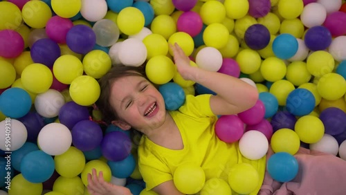 Smiling girl in a paddling pool in playing centre with plastic balls photo