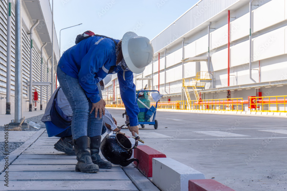 Worker sealing asphaltic joint for construction joint on concrete pavement, concrete joint between road and gutter