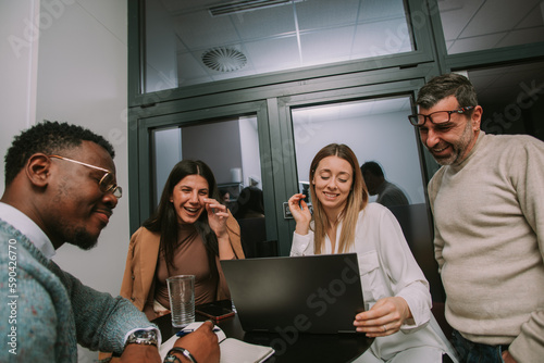 A photo of happy multiracial coworkers having fun while working together at modern co working space
