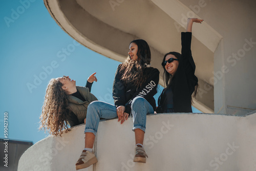 Two girls having a conversation and smiling while their brunette friend is enjoying the panorama