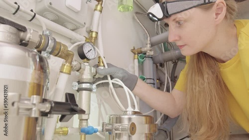 Woman plumber replaces clean water filter in kitchen