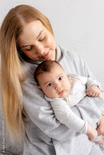 Mom and baby play on the bed. Mother and son, happy family, beautiful blonde girl and cute baby at home.