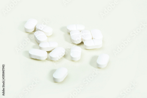 Close up shots of medicine tablets and capsules on white background. White and colored tablets placed in a group.