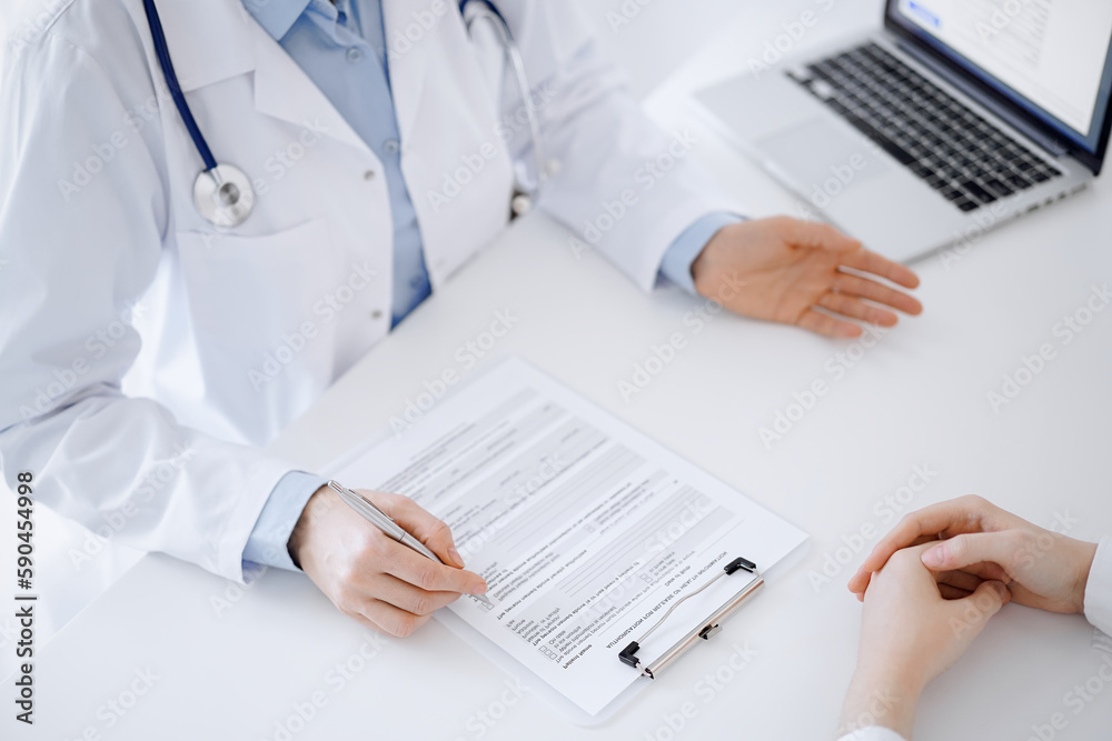 Doctor and patient discussing current health questions while sitting opposite of each other and using clipboard at the table in clinic, just hands closeup. Medicine concept Doctor and patient discussing current health questions while sitting opposite of each other and using clipboard at the table in clinic, just hands closeup. Medicine concept