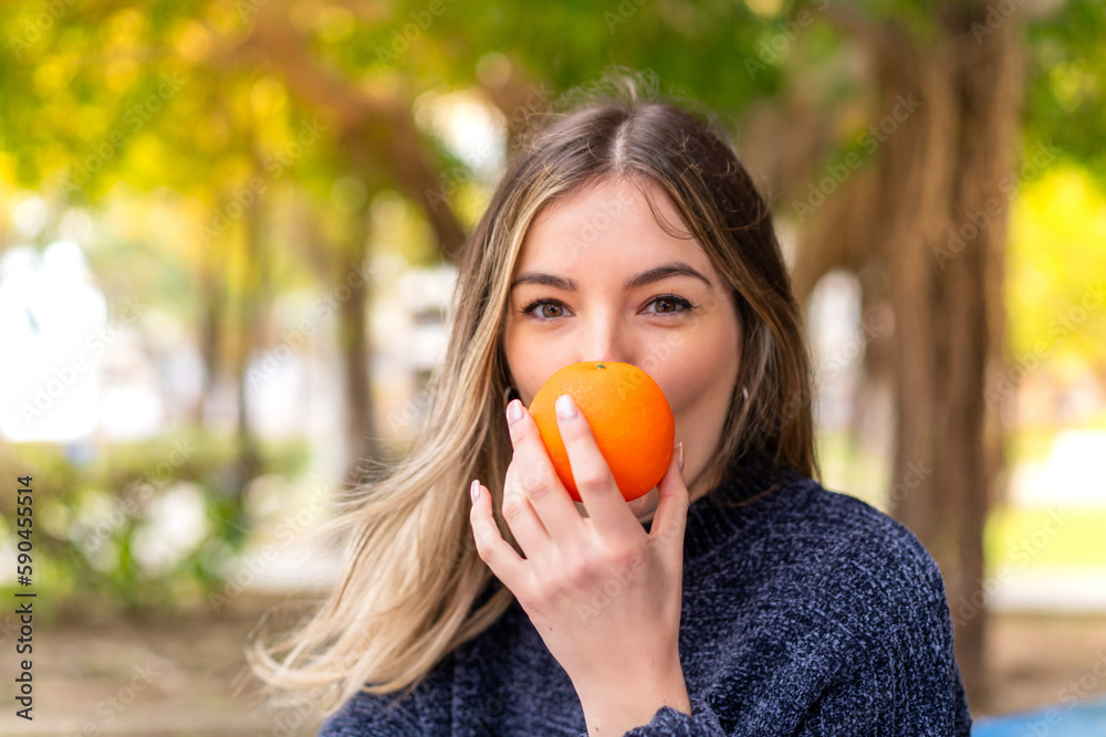 Young pretty Romanian woman holding an orange at outdoors Young pretty Romanian woman holding an orange at outdoors