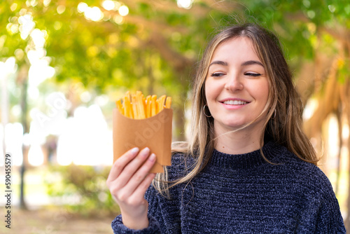Young pretty Romanian woman holding fried chips at outdoors with happy expression