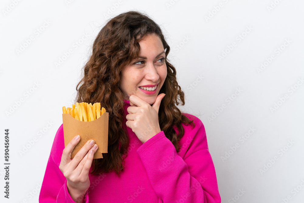 Young caucasian woman catching french fries isolated on white background thinking an idea and looking side Young caucasian woman catching french fries isolated on white background thinking an idea and looking side